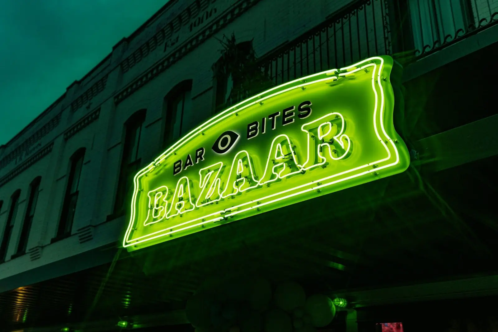 The green neon Bazaar sign glowing over the historic San Marcos square at night